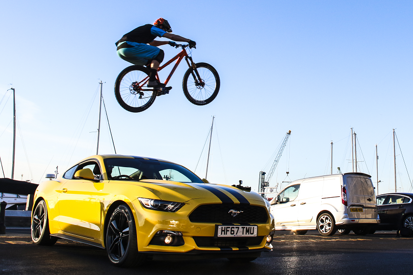Ben Moore in the air jumping over a car on his bike at Poole Quay